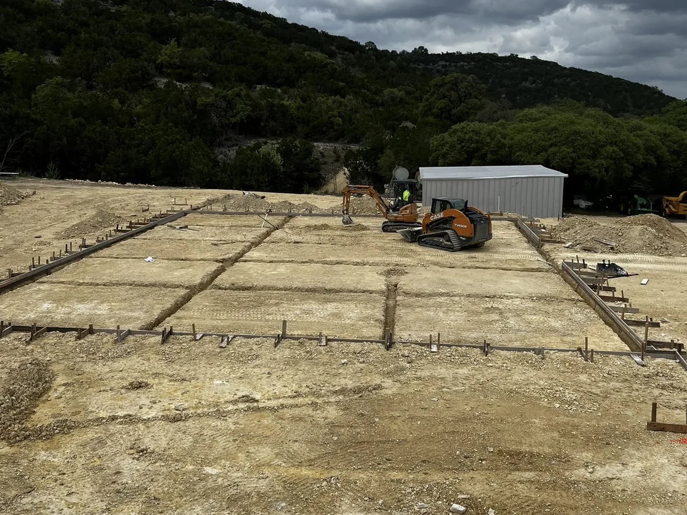 Graded building pad with beam trenches and formwork set before the shop foundation pour