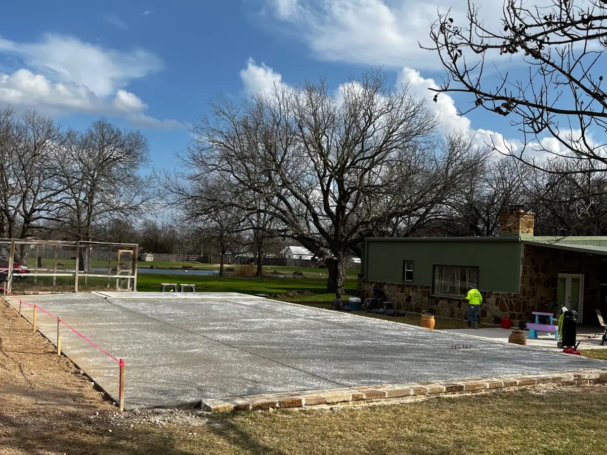 Thick concrete RV parking pad poured beside a metal shop building